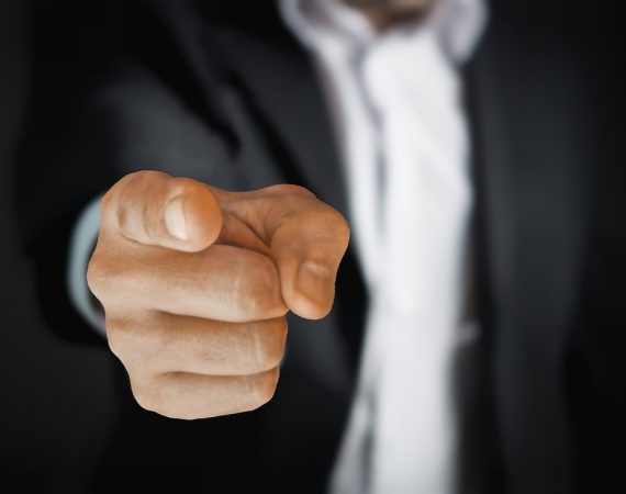 Mano de una persona señalando directamente con el dedo, representando acusaciones o imputaciones en un contexto legal.