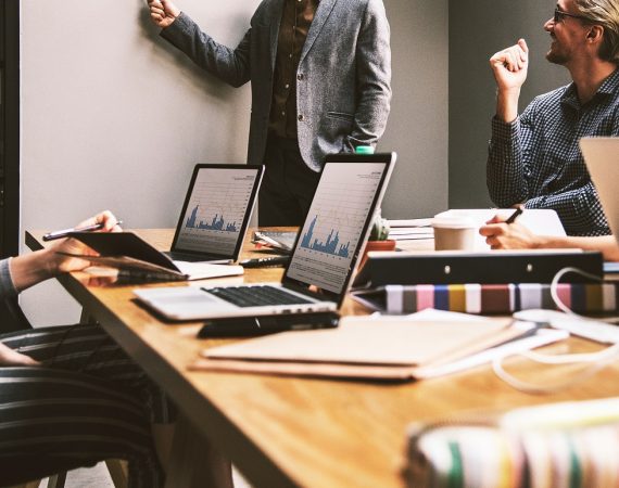Profesionales en una reunión de negocios revisando gráficos y estrategias, ilustrando planificación y asesoría legal.